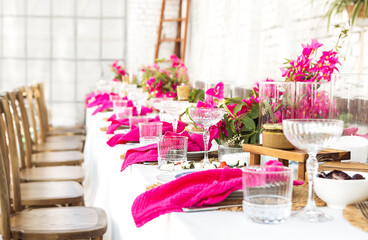 A set festive table in the open air. The table is decorated with candles and flowers