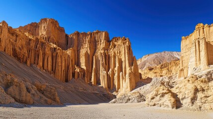 Fototapeta premium Majestic sandstone cliffs rise dramatically against a clear blue sky in a remote desert valley during midday