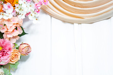 Elegant flower arrangement on white wooden background with fabric drape, romantic wedding backdrop