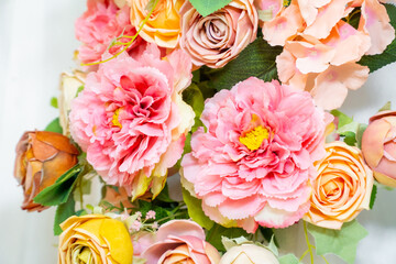 A stunning floral arrangement featuring yellow and pink roses with lush green leaves on a clean white background, ideal for weddings and elegant event decorations