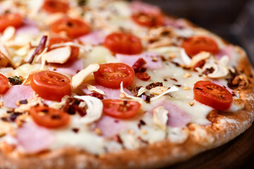 Pizza with ham, cherry tomatoes and mozzarella cheese. Wooden background. Soft focus. Close up.