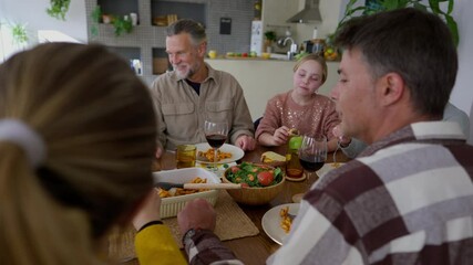 Extended family, including grandparents, parents, and children, are gathering around a dining table, sharing a meal and engaging in conversation, creating a warm and joyful atmosphere