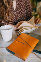 A woman sitting at a table with a journal, coffee, and flowers around, concentrating while holding a bouquet in a calm and peaceful atmosphere.