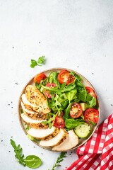 Green salad with chicken steak and fresh vegetables at black table. Top view with copy space.