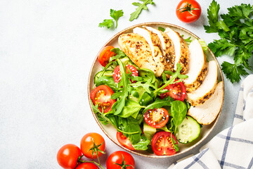 Chicken salad with grilled meat and vegetables at black table. Top view with copy space.