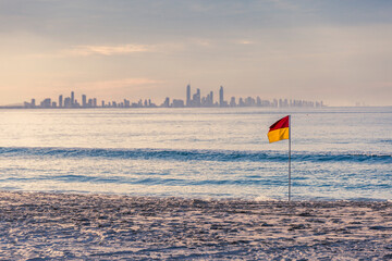 Surf Life Saving patrol flag on beach with city in background