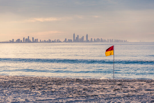 Surf Life Saving patrol flag on beach with city in background