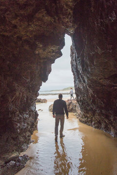 A man walks through a cave on the beach