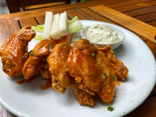 Chicken wings served with vegetables and blue cheese dip on a white plate
