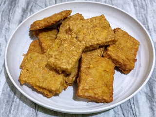 Crispy flour fried tempeh, served on a white plate.