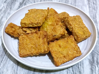 Crispy flour fried tempeh, served on a white plate.