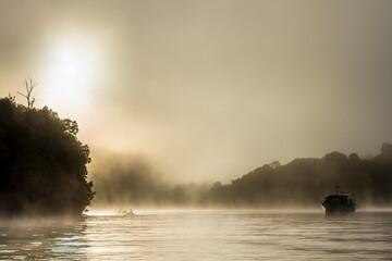 Silhouette of old wooden boat on the water in fog
