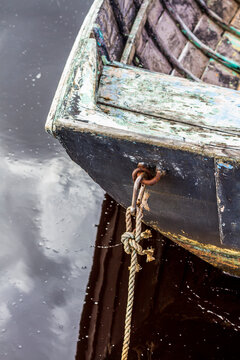 The stern of an old wooden boat moored.