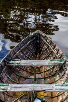 The bow of an old wooden boat in the water.