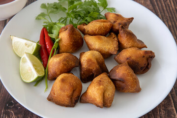 Indian fried Samosa filled with spiced potato, served with lime wedges and sauce
