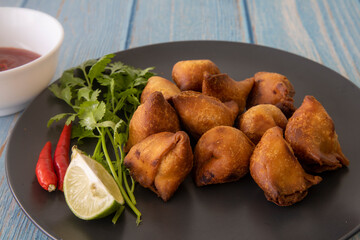 Indian fried Samosa filled with spiced potato, served with lime wedges and sauce