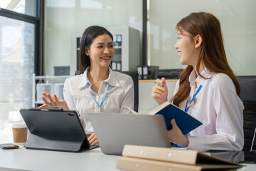 Obraz premium Two busy happy business woman executive leaders team using laptop working on computer at work desk having conversation on financial project at meeting in office.