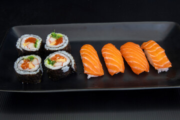 Japanese salmon maki rolls and salmon nigiri on black plate