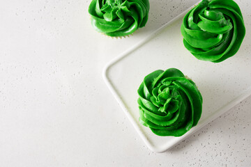 St. Patrick's Day tasty cupcakes with green whipped cream on white background. Close up. View from...