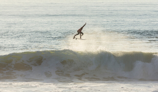 Fantastic surfer aerial maneuver at sunset - Powered by Adobe