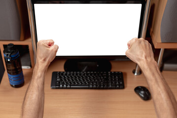 Fototapeta premium Closeup of joyful man at home office celebrating success with fists raised. Man showing emotions while looking at white screen on monitor, gesturing from behind
