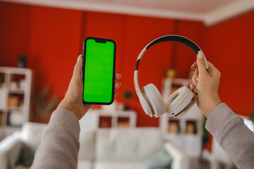 Person Holding Phone and Headphones in Cozy Living Room