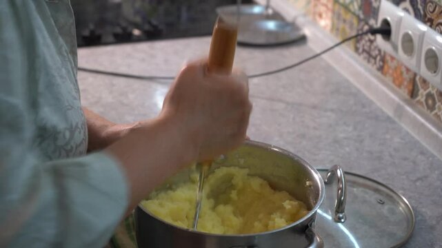 Hands mashing potatoes in a masher. Cooking food at home
