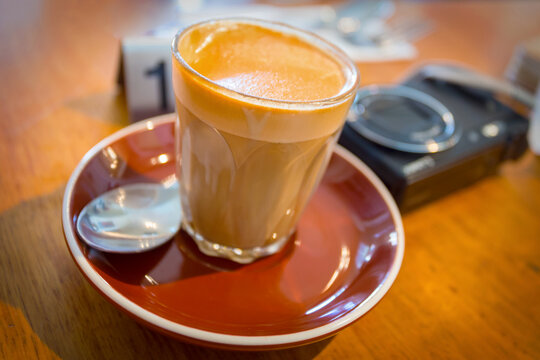 A coffee and camera lying on a table in a cafe