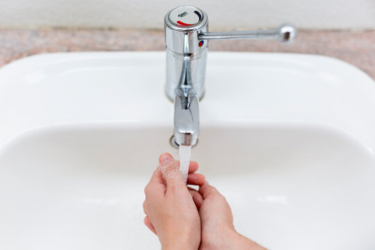Washing hands in a public bathroom.