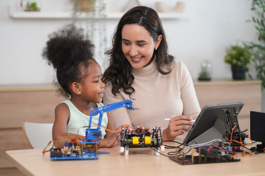 tutor providing a student in STEM lesson in class,a female teacher using tablet computer teach kid on robot circuits
