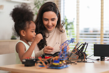 tutor providing a student in STEM lesson in class,a female teacher using tablet computer teach kid on robot circuits