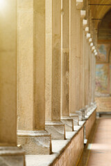 Row of ancient stone columns in corridor, illuminated by sunlight. Photo was taken with shallow depth of field