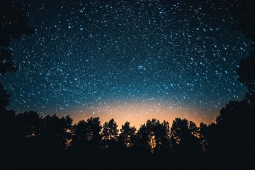 Naklejka premium Enchanting nightscape featuring celestial star trails above a serene forest silhouette offering a sense of wonder and cosmic exploration under the vast night sky
