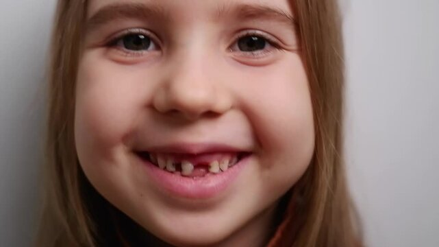 Close-up portrait of smiling little girl showing her missing baby teeth