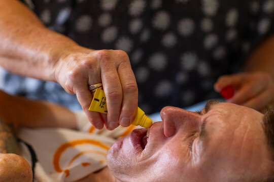 Middle aged woman applying lip balm on lips of son with disability