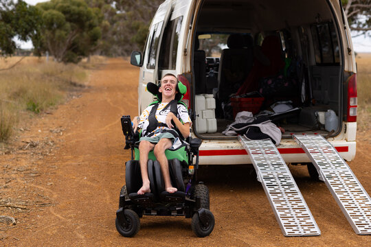 Young man with disability on a wheelchair behind the van with ramp for accessibility