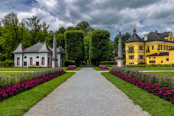 Obraz premium Weg führt durch den Park auf die Gebäude vom Schloss Hellbrunn in Salzburg