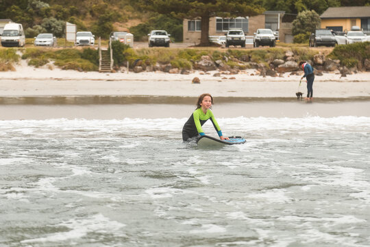 Boy with surfboard in shallow water on Bridgewater Beach at Portland Victoria