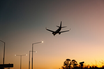 Silhouette of commercial airplane flying in the sky at sunset