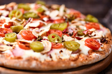 Pizza with ham, cherry tomatoes and mozzarella cheese. Wooden background. Soft focus. Close up.