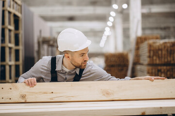 Construction worker checking wooden planks in warehouse for modular building
