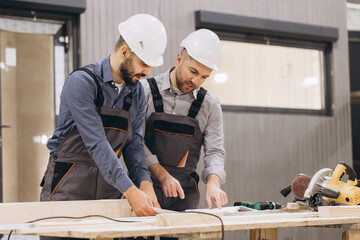 Construction workers examining blueprint in modular building factory