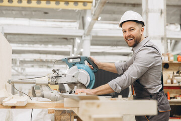 Carpenter cutting wooden plank with circular saw in workshop