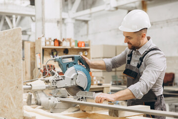 Carpenter cutting wood plank using circular saw in workshop
