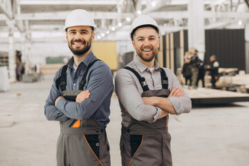 Construction workers smiling with arms crossed in modular building factory