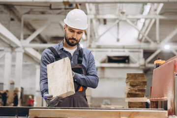 Carpenter inspecting wooden plank in timber factory for modular building