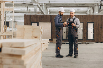 Construction workers using digital tablet in modular building factory