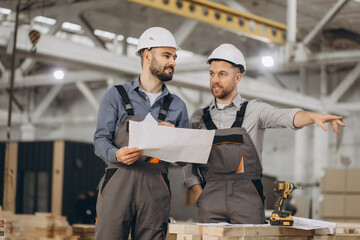 Engineers discussing blueprint in modular building factory