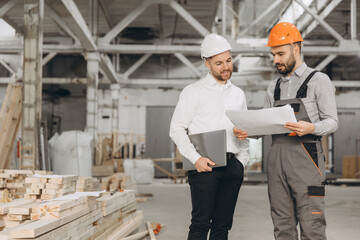 Engineers reading blueprint in modular building factory