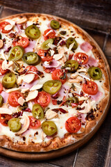 Pizza with ham, cherry tomatoes and mozzarella cheese. Wooden background. Soft focus. Close up.